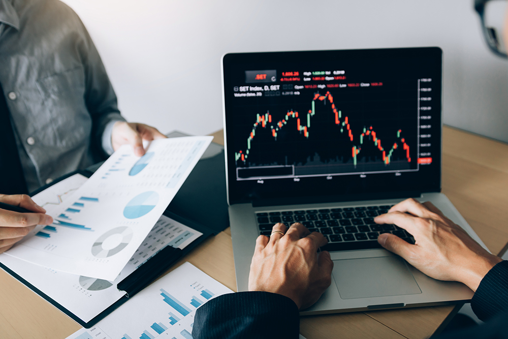 Two investors are working together with analyzing the stock data graphs.