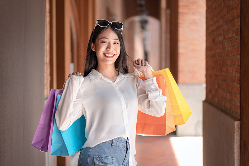 Portrait of Asian girl excited beautiful girl wearing sunglasses happy smiling with holding shopping bags enjoying in shopping relaxed expression, Positive emotions shopping, lifestyle concept.